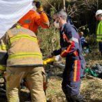Carreta com madeira tomba em estrada rural e motorista fica preso às ferragens