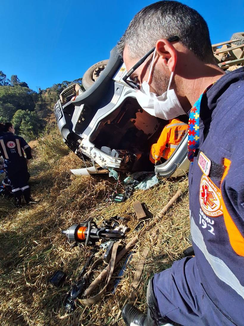 Carreta com madeira tomba em estrada rural e motorista fica preso às ferragens